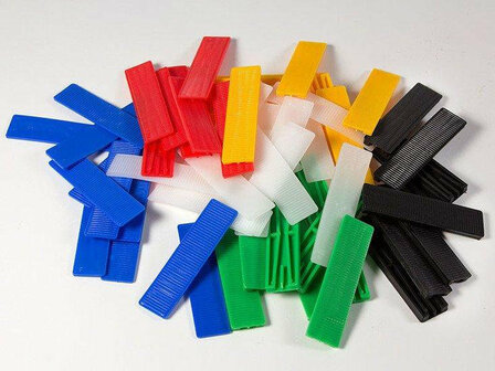 Een kleurrijke verzameling plastic clips in blauw, rood, groen, geel, wit en zwart, verspreid over een lichte ondergrond.