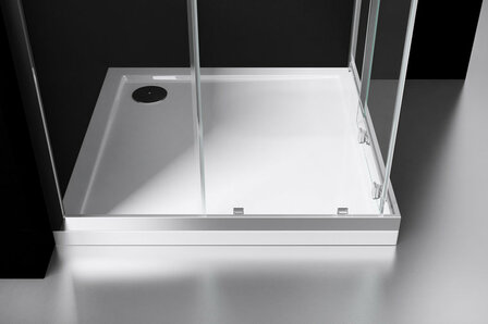 Een moderne douchebak in wit acryl met glaswanden en een chroomkleurige afvoer, geplaatst op een strak zwart keramisch oppervlak.