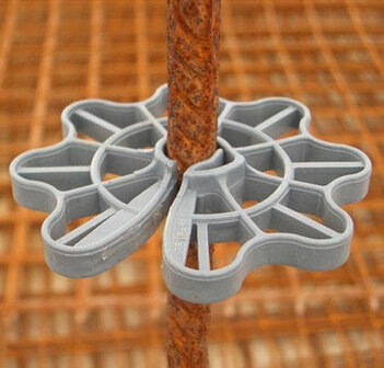 Grijze kunststof verbindingsclip die een ijzeren staaf vasthoudt, geplaatst op een achtergrond van bruin ruw ijzer.