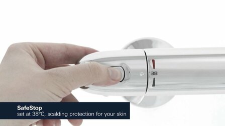 Glanzende, chromen kraan met een temperatuurregelknop, wit wandpaneel en duidelijke merkindicatie voor warmwaterbeveiliging.