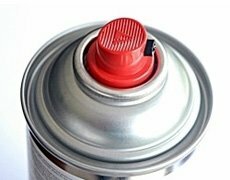 Ronde spuitbus met een glanzende zilveren kleur en een opvallende rode spuitdop bovenop.