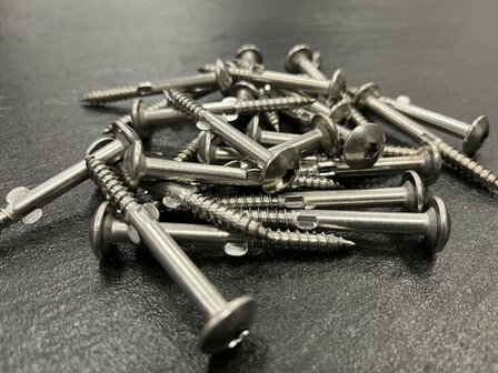 Een verzameling metalen schroeven met een glanzende afwerking, verspreid over een donkere ondergrond.