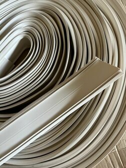 Grijze kunststof strips in een opgerolde spiraalvorm, met een gladde afwerking en duidelijke randen, op een kartonnen ondergron