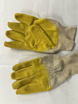 Gele werkhandschoenen met een grijze ribbelrand, zichtbaar versleten en met een ruw patroon op de vingers.