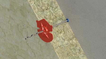 Een metalen schroef met een rode kunststof schijf is in een lichte, zachte ondergrond geschroefd.