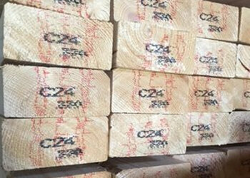 Stapels onbewerkte houten planken, met een lichte kleur en zichtbare merktekens in rood, netjes geordend in een compositie.