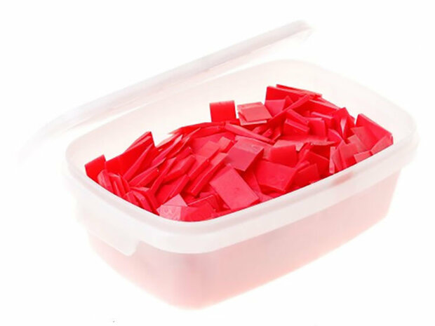 Transparante plastic doos met een witte deksel, gevuld met kleine rode plastic stukjes.