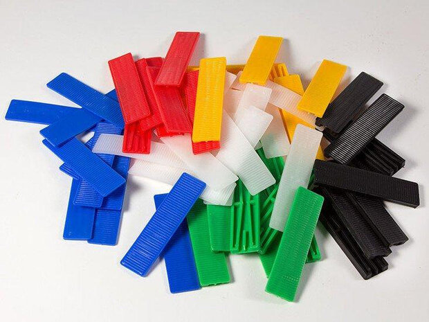 Kleurrijke plastic clips in blauw, rood, groen, geel, wit en zwart, verspreid over een witte ondergrond.