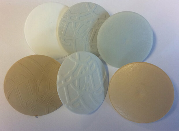 Zes ronde schijven in verschillende kleuren: wit, crème, lichtblauw en beige, met gladde en reliëfstructuur.