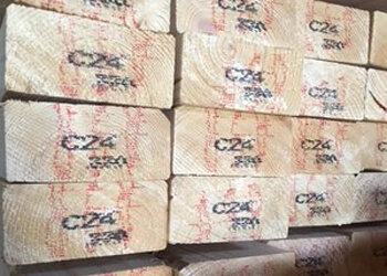 Gestapelde houten planken met een lichte kleur en rode merkaanduidingen, zichtbaar in een rechte compositie.