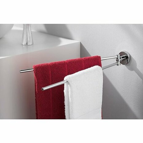 Een chromen handdoekrek met een rode en een witte handdoek, geplaatst tegen een lichte muur.