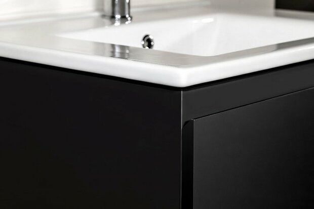 Zwarte onderkast met hoogglans wit wastafelblad en chroomkleurige kraan aan een moderne badkamerwand.